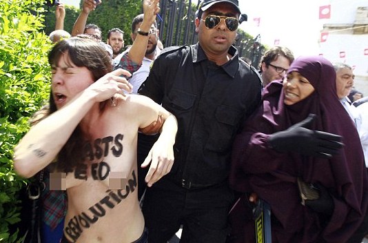 Police officers detain an activist from the women's rights group FEMEN during a protest in front of Tunisia's Ministry of Justice in Tunis
